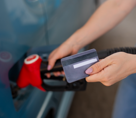 image: photo of a person pumping gas with a credit card in their other hand. 