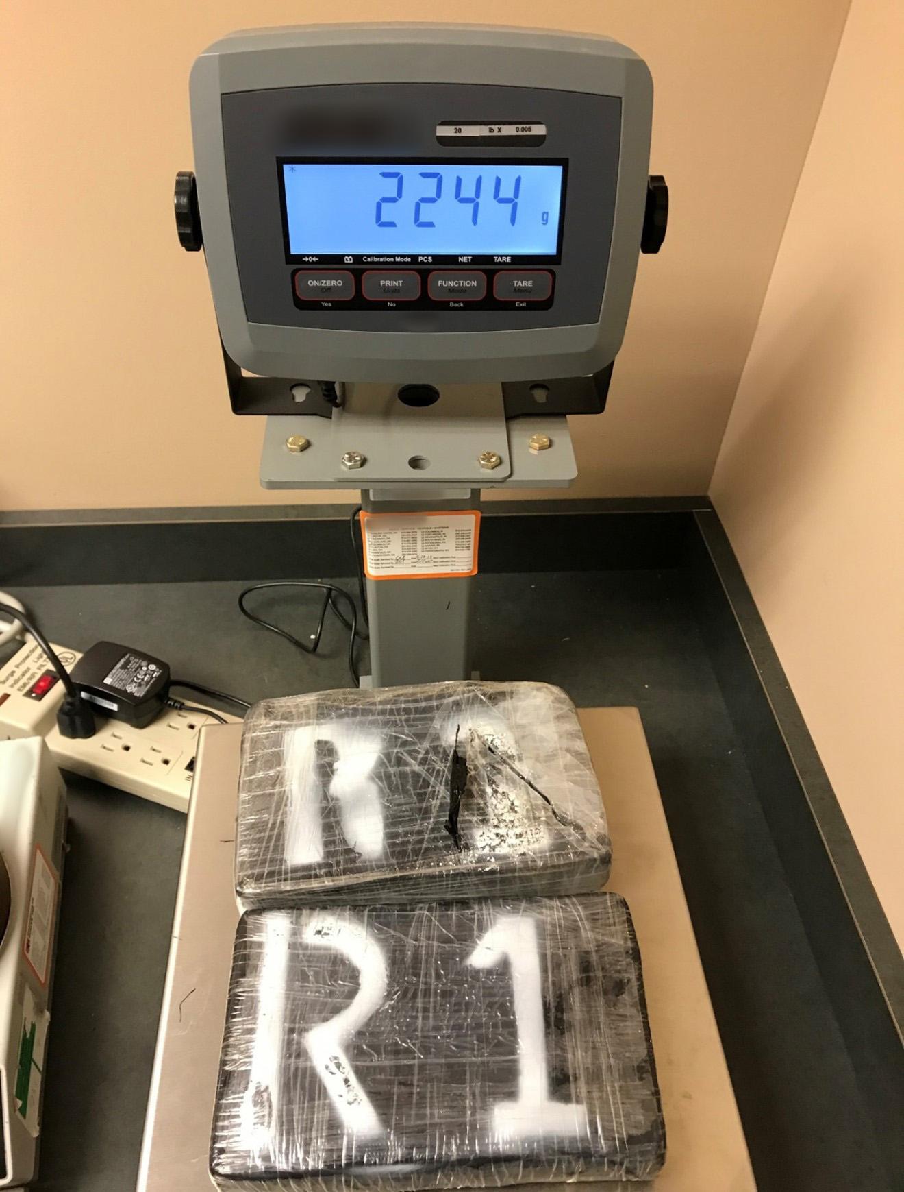 Plastic wrapped packages labeled R1 on a scale weighing 2244 grams.