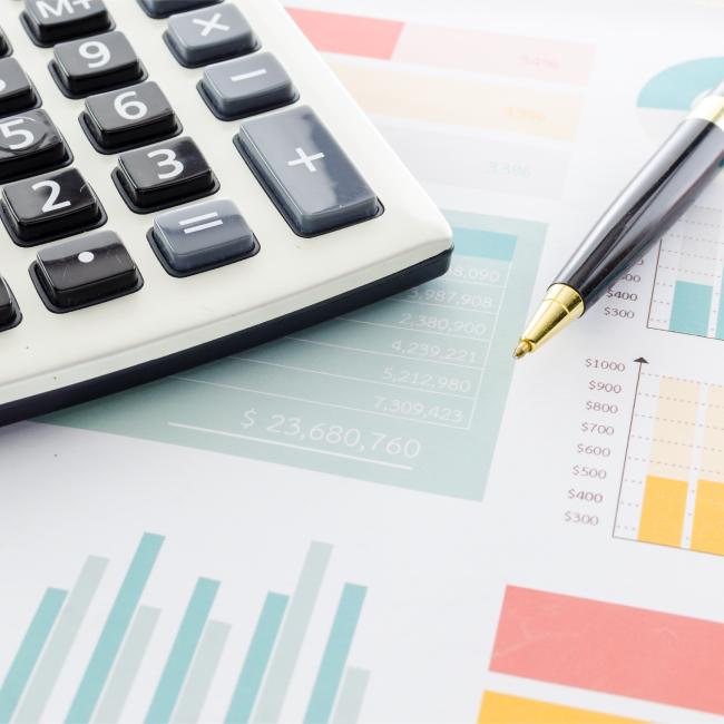 Photo of a calculator and generic financial graphs. 